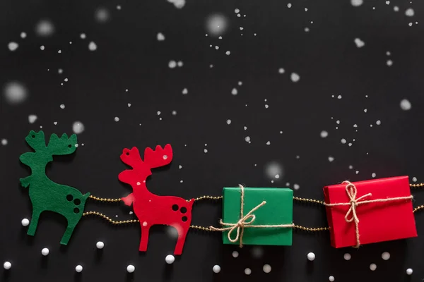 驯鹿响尾蛇礼物和礼物盒圣诞节的概念超过黑色背景与雪 顶视图平铺 — 图库照片