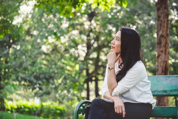 亚洲女商人坐在户外公园里 带着抄袭的空间思考 — 图库照片