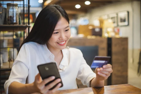 コーヒーショップカフェでオンラインショッピングのためのスマートフォンやクレジットカードを使用して若い美しいアジアの女性 — ストック写真