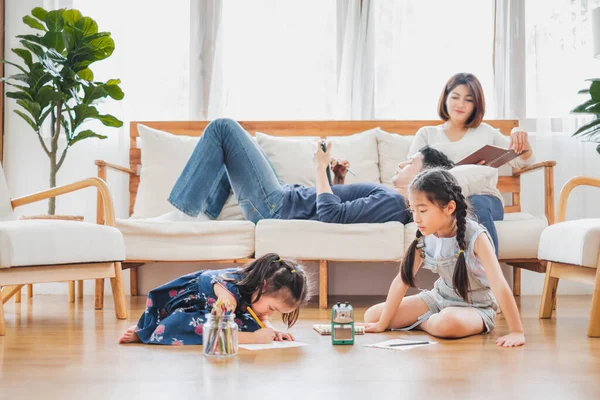 Güzel kızları olan Asyalı bir aile evdeki oturma odasında resim yapıyor.