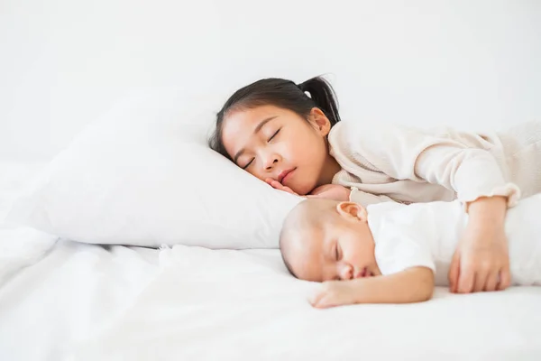 亚洲可爱的女孩抱着孩子睡在白色的床上 — 图库照片