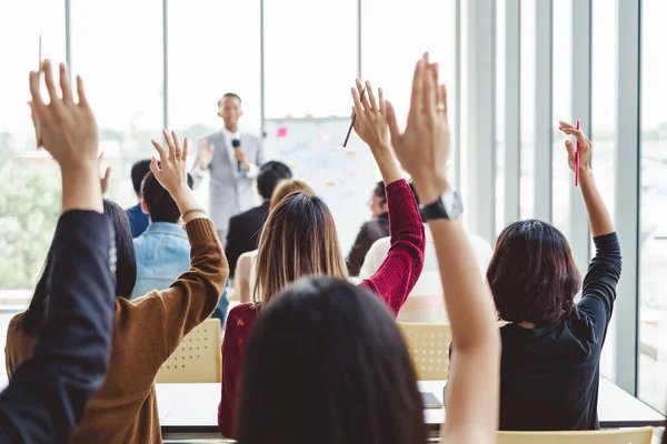 Bir grup iş adamı toplantı odası seminerinde konuşmacı ile aynı fikirde olmak için ellerini kaldırdı.