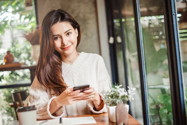 年轻的亚洲美女用智能手机做生意 网上购物 网上银行 在咖啡店咖啡店 — 图库照片