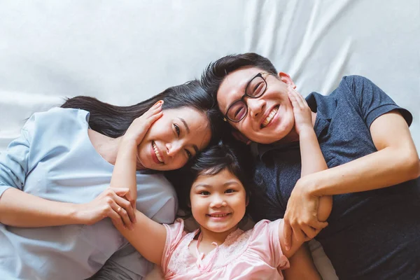幸せと笑顔でベッドルームにベッドルームに横たわっているアジアの家族 トップビュー — ストック写真