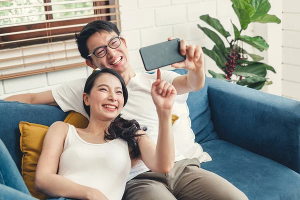 Young Asian couple lover taking selfie by mobile phone at home, relax and lifestyle at home concept