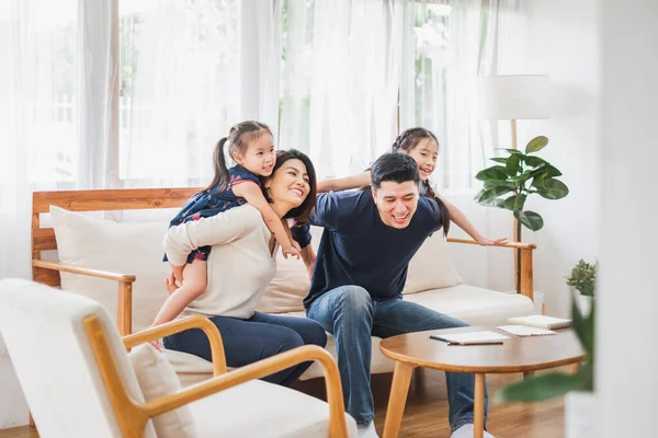 Mutlu Asyalı aile kanepede, evde birlikte oynuyorlar.