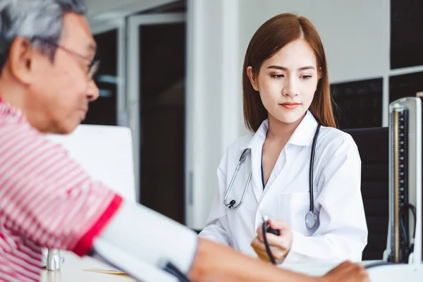 Asian doctor checking  blood pressure of old man patient at hospital, asian medical concept