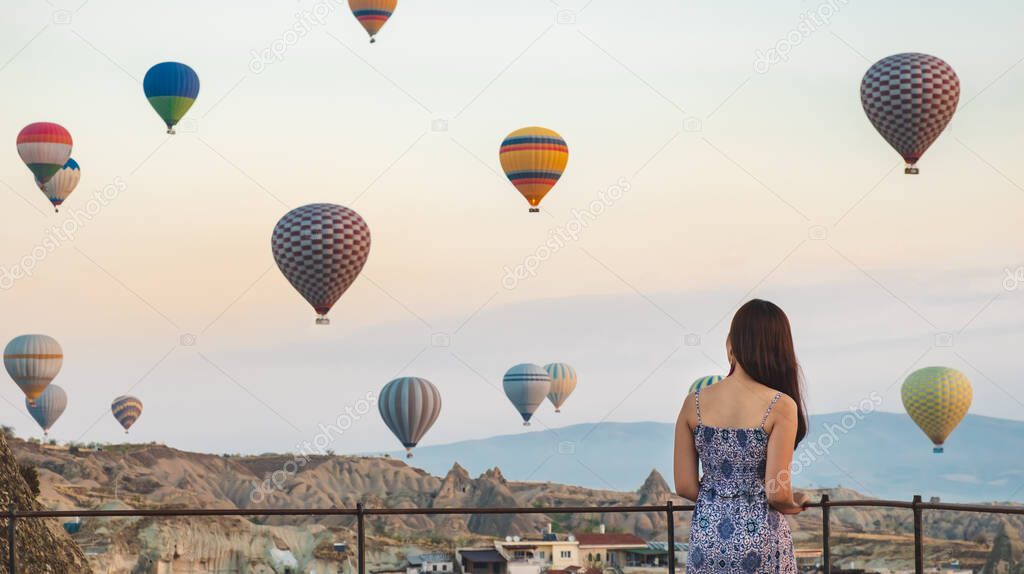 Asian beautiful woman standing over hot air balloons in Cappadocia, Goreme, Turkey