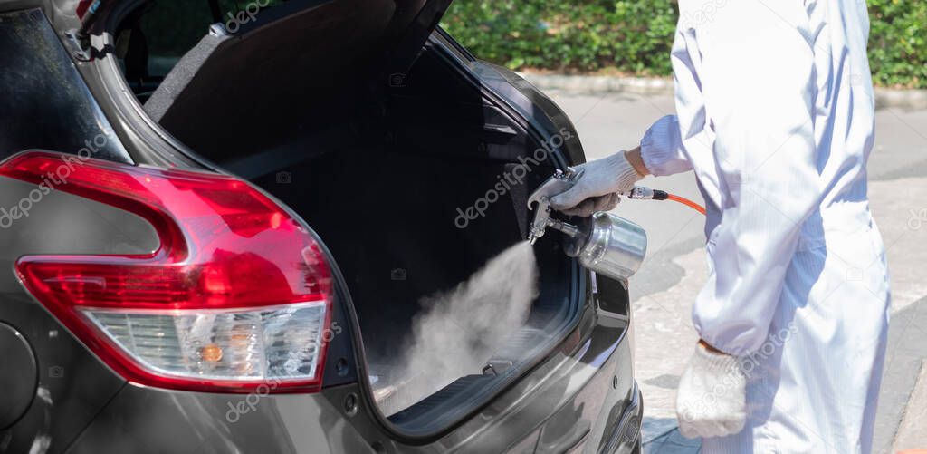 Close up hand of specialist cleaner wearing personal protective equipment PPE using chemical alcohol spray cleaning inside car to disinfect and decontaminate coronavirus covid-19