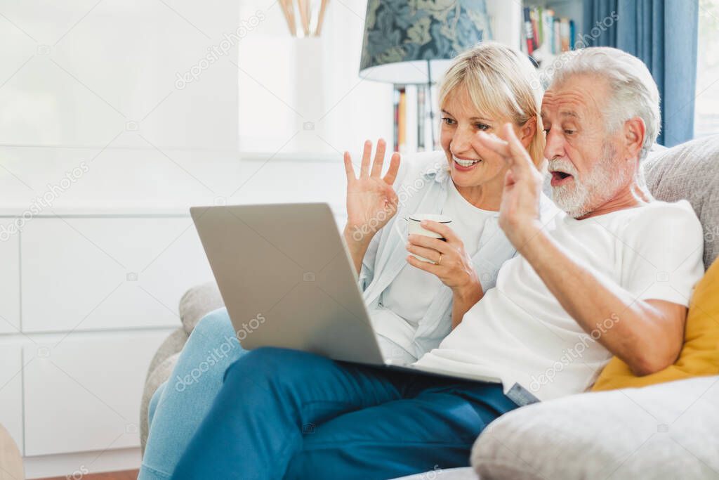 Couple senior using computer laptop on sofa at home for online shopping, surfing internet