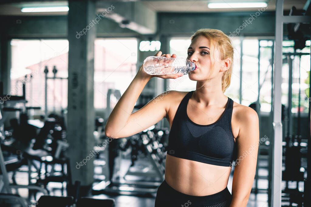 Woman drinking water after finish workout at sport gym, with smile happy and relax