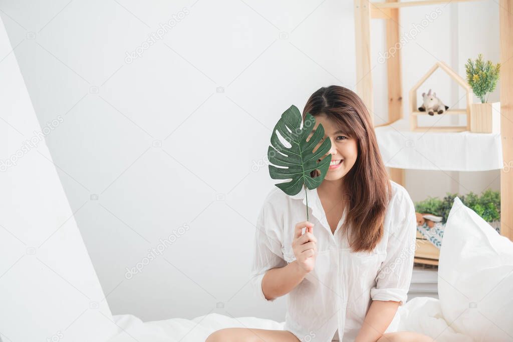 Portrait beautiful Asian woman lifestyle with green leaf in bed room