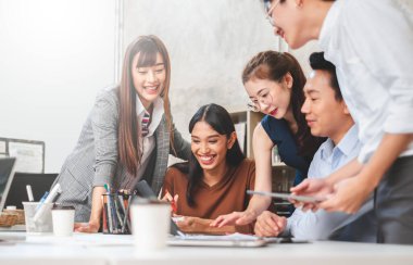 Bir grup Asyalı iş adamı ve yaratıcı tasarımcı ofisinde toplanıyor.