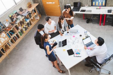 Bir grup Asyalı iş adamı ve yaratıcı tasarımcı ofisinde toplanıyor.