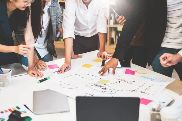 Bir grup Asyalı iş adamı ve yaratıcı tasarımcı ofisinde toplanıyor.