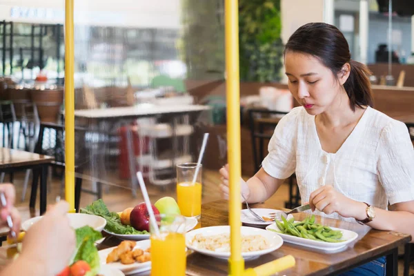 Asiatisk Kvinde Sidder Adskilt Restaurant Spiser Mad Med Bord Skjold - Stock-foto