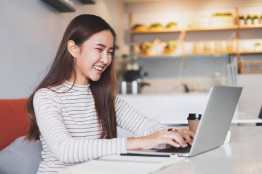 Genç Asyalı kadın çalışmak ve iş bulmak için dizüstü bilgisayar kullanıyor.