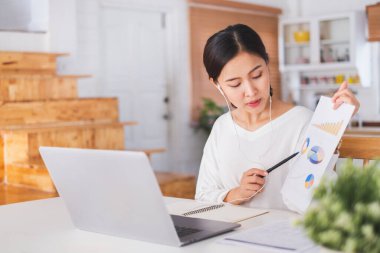 Genç Asyalı iş kadını, iş arkadaşlarıyla evde ve sanal video konferansında çalışıyor. İnternette çalışıyor, sosyal mesafeler nedeniyle video görüşmesi yapıyor.