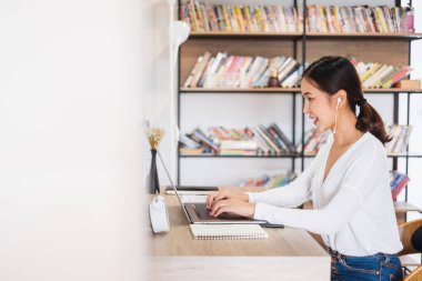 Genç Asyalı iş kadını iş arkadaşlarıyla evde çalışıyor ve iş arkadaşlarıyla sanal video konferansı yapıyor, internet üzerinden çalışıyor, evdeki sosyal mesafeler nedeniyle video görüşmesi yapıyor.