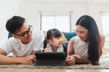 Mutlu Asyalı aile tablet, dizüstü bilgisayar, oyun oynamak için telefon film izlemek için evde dinleniyor teknoloji yaşam tarzı konsepti için dinleniyor