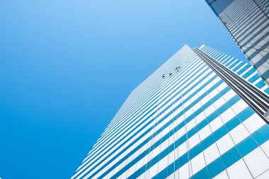 Bir grup işçi, mavi gökyüzü üzerinde gökdelen inşa eden gökdelenlerin camlarını temizliyor.