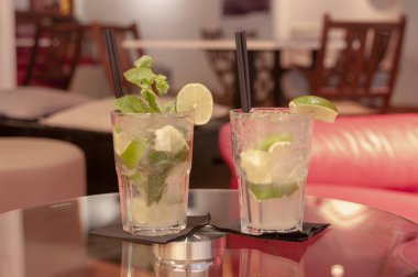 Kokteyl mojito ve caipirinha. İki kokteyl cam masa üzerinde.