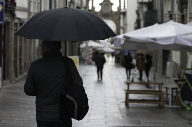 Braga, Portekiz, Avrupa ve şemsiye yürüme ile adam yağmurlu gün