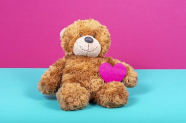 Oyuncak ayı iki renk arka plan üzerinde keçe kalp ile