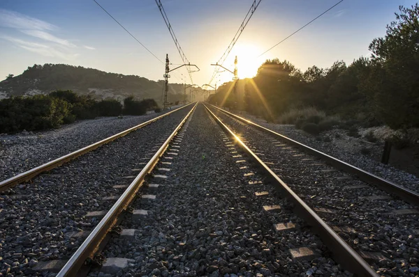 Train tracks at sunset with bright sun and metal reflections