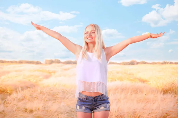 Beautiful girl at sunrise in a wheat field. The girl rejoices that summer has come. The girl is trying to fly. Enjoys the summer. Feel freedom. I believe I can fly. A young girl walks the wheat field