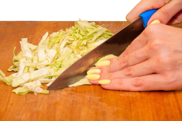 Genç kadın beyaz bir arka planda bir mutfak masasında lahana dilimleri. Kız salata hazırlıyor. Salata hazırla. Lahana dilimlenmiş dilimleri