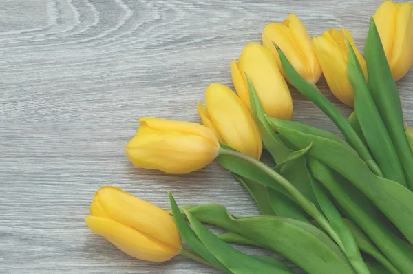 Sarı Lale güzel bir buket ahşap gri masada yakın yatıyor. Masada narin çiçekler.