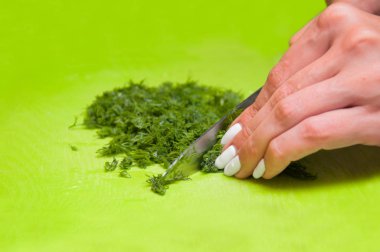 Kız yeşil bir tahta yakın çekim dereotu keser.