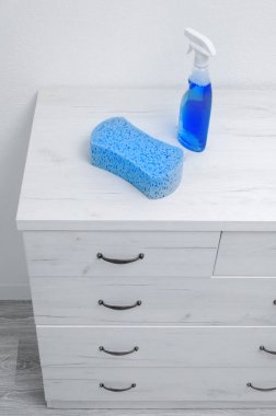 Büyük sünger ve beyaz bir duvara karşı çekmecegri bir göğüs üzerinde temizleme spreyi. Dairenin temizliği.