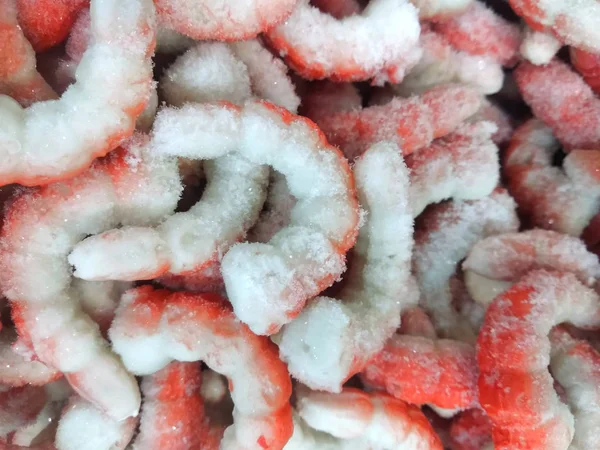 Frozen shrimp closeup. Peeled shrimp. Orange background.