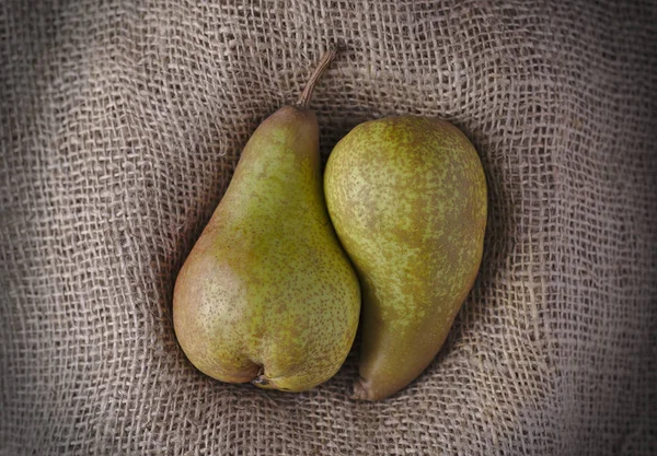 two juicy pears together in a cuddling shape on burlap or Hessian material