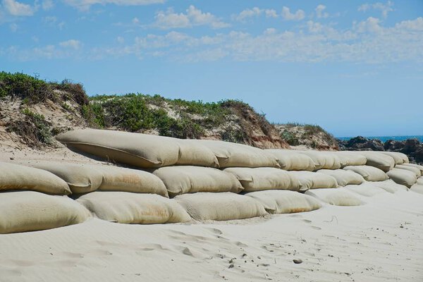 large burlap or hessian sandbags stopping soil erosion on a beach during high tide and stormy days