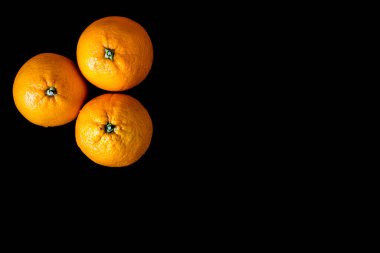 Siyah arka planda sol köşede üç portakal. Vejetaryen yemeği