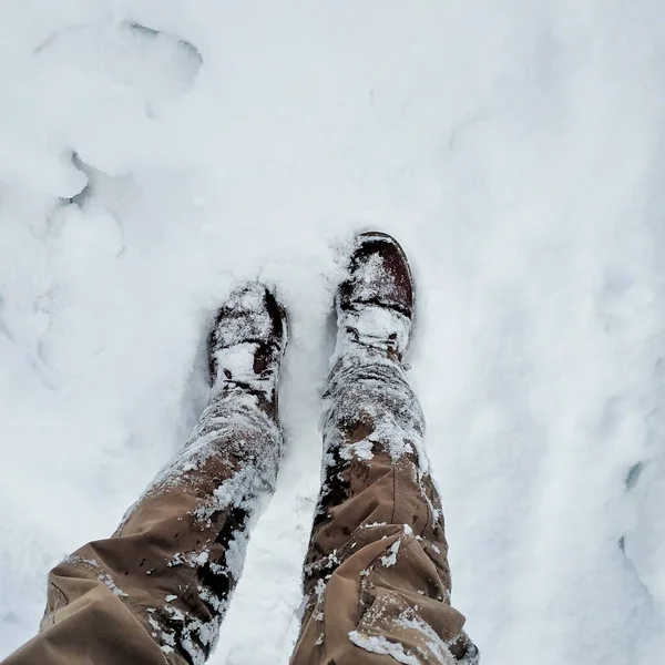 穿着棕色裤子和靴子的两条腿在白雪中被挖的头像 冬季旅行 — 图库照片