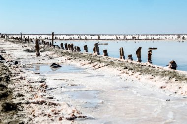 Tuz madenciliği. Yollu pembe tuz gölü, mavi gökyüzü ve ahşap çit. Yazın seyahat.