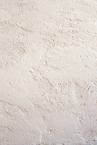 Açık bej alçılı beton duvar, boyanmış pis boyanmış alçı. Düzensizlikler ve kabarcıklarla soyut ışık arkaplanı. Dikey görünüm