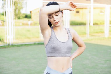 Kadın sporcu fitness antrenmanından sonra dinleniyor. Yüzünden güzel, güçlü, esmer bir terin portresi. Egzersiz yaptıktan sonra soluklanan güzel genç bir kadın..