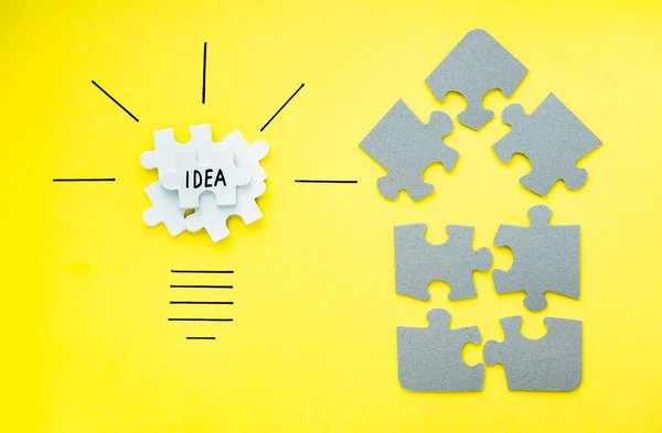 Light bulb over yellow background in vision and idea conceptual image. Conceptual image of creativity and idea. Jigsaw Puzzle pieces on yellow background top view.