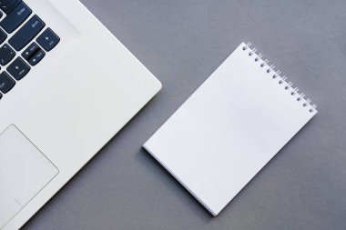 Üst görünüm masası, Modern ofis çalışma alanı dizüstü bilgisayarı, not defteri ve çalışma arka planı için ofis malzemeleri. Çalışma alanı kavramı. Gri arka plan. Boşluğu kopyala