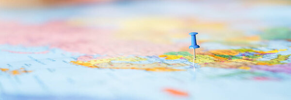 Pushpin showing the location of a destination point on a map. Travel destination, pin on the map. Very selective focus, blur on all edges and special lightening.