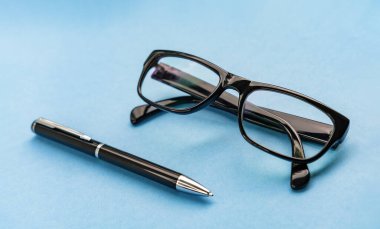 Modern yaşam tarzı sabit konsept tasarımı için mavi arka plandaki kalem ve gözlükleri kapatın. Malzemeli mavi ofis masası. Modern ofis masası Çalışma Alanı Çalışma Arkaplanı.