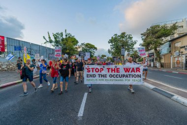 Hayfa, İsrail - Eylül 06, 2025: İnsanlar çeşitli işaretlerle bir protesto yürüyüşüne katılıyor, savaşın sona ermesi ve rehine anlaşmasının tamamlanması yönünde çağrıda bulunuyorlar. Hayfa, İsrail