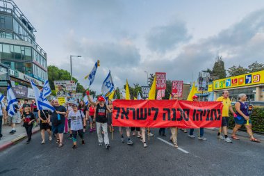Hayfa, İsrail - 06 Eylül 2025: Çeşitli tabelaları ve bayrakları olan insanlar, savaşın sona ermesi, rehine anlaşmasının tamamlanması ve yeni seçimlerin başlatılması için düzenlenen protesto mitingine katıldılar. Hayfa, İsrail