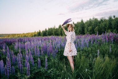 Lupin buketi tutan hasır şapkalı sarışın bir kız..