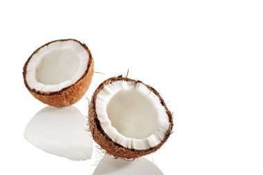 Beyaz bir yüzeyde iki yarım hindistan cevizi.